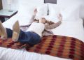 Happy woman falling backwards on hotel bed