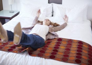 Happy woman falling backwards on hotel bed
