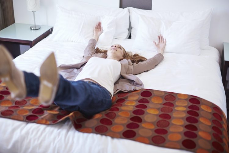 Happy woman falling backwards on hotel bed