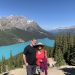 Middle aged couple traveling in Canadian Rockies, posing for photo by beautiful Peyto Lake in Banff