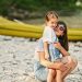 Mother with daughter against canoe in rocky shore of a calm river
